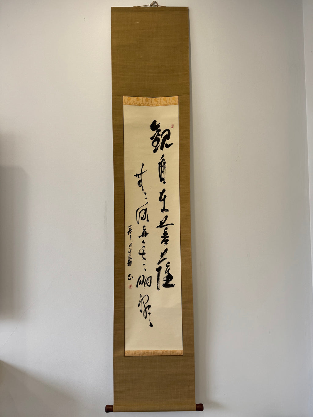 Vertical scroll with calligraphy on a plain wall