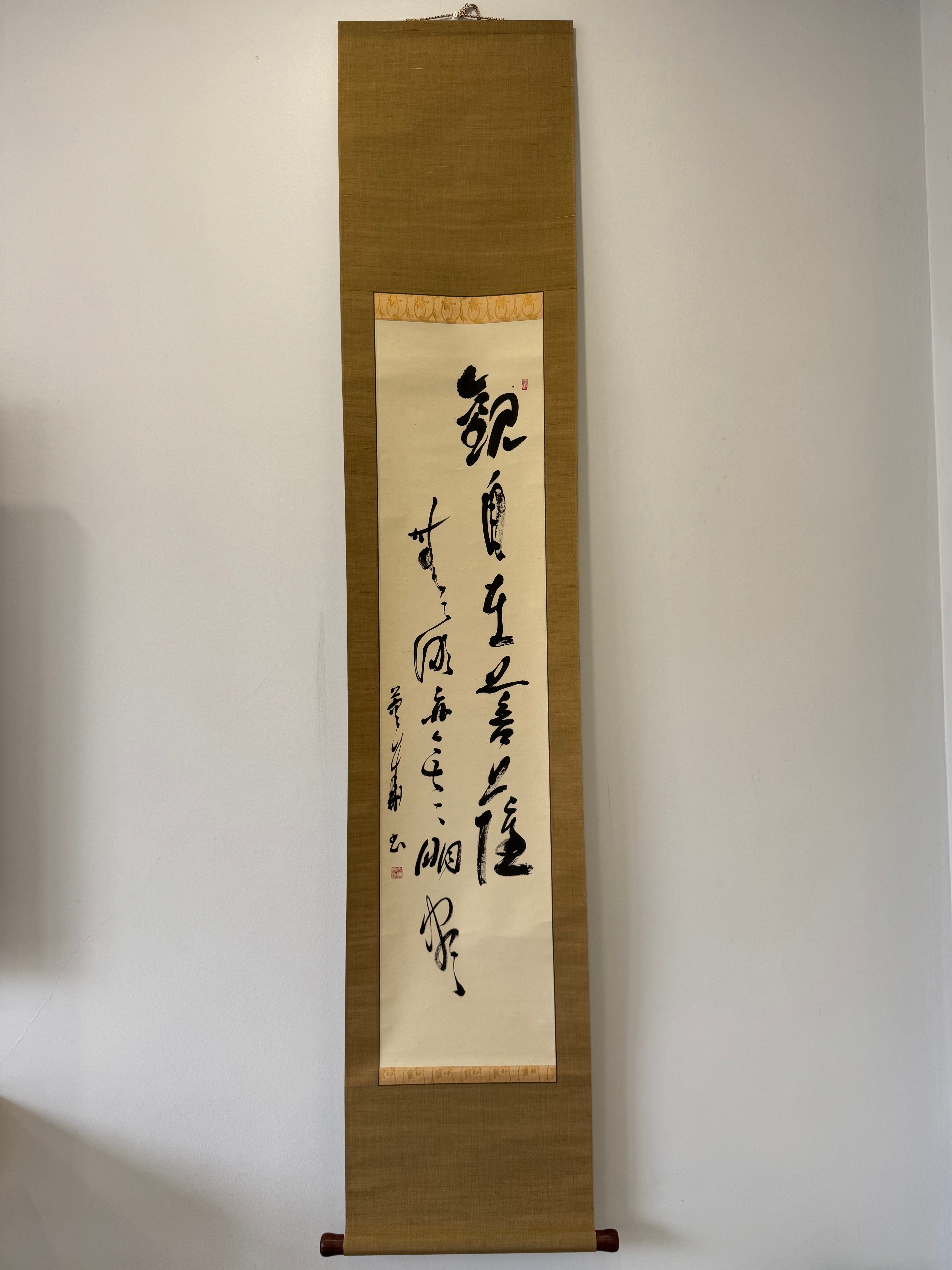Vertical scroll with calligraphy on a plain wall