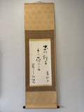 Traditional Japanese calligraphy scroll on a plain wall