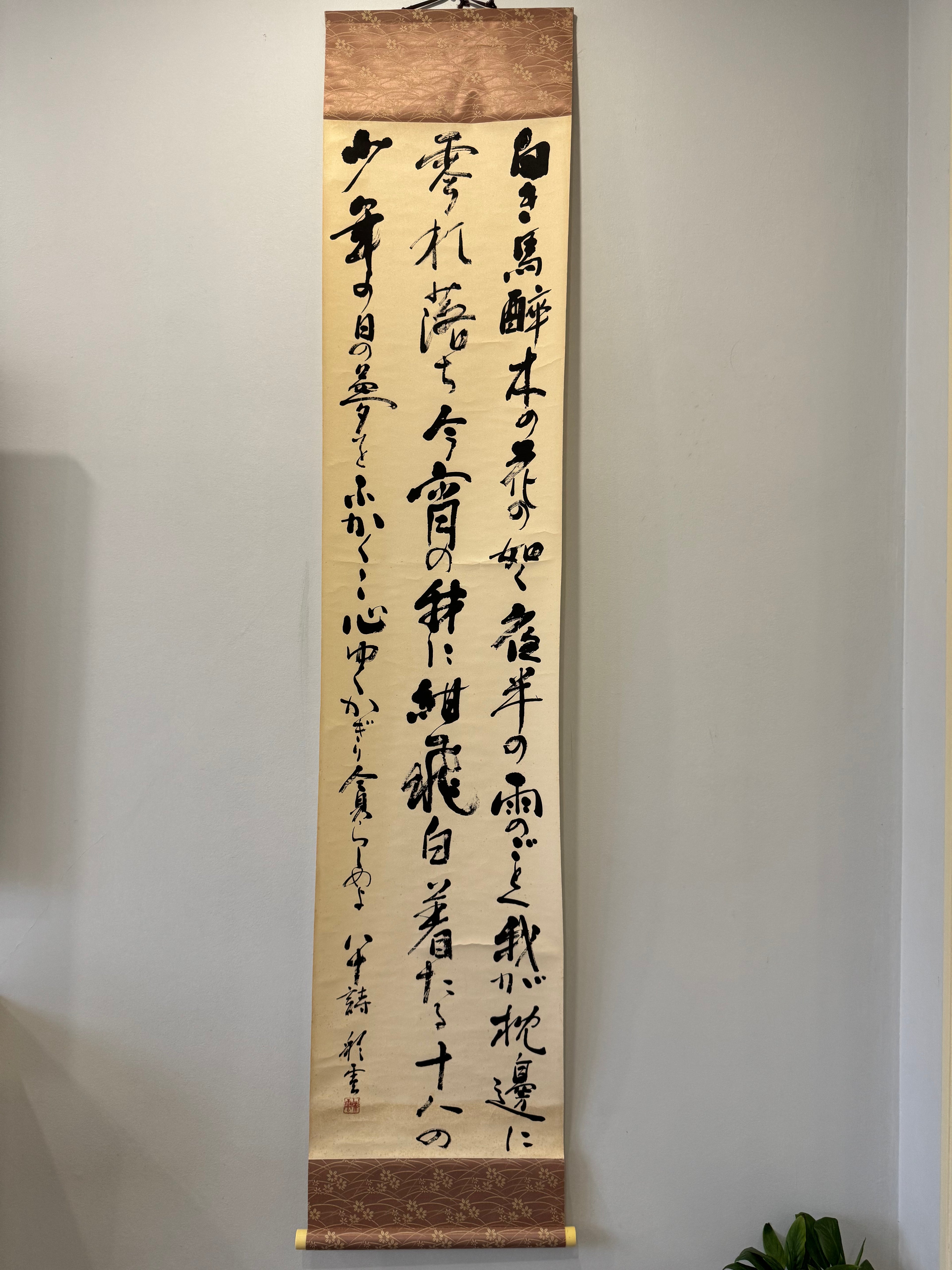 Vertical scroll with calligraphy on a plain wall