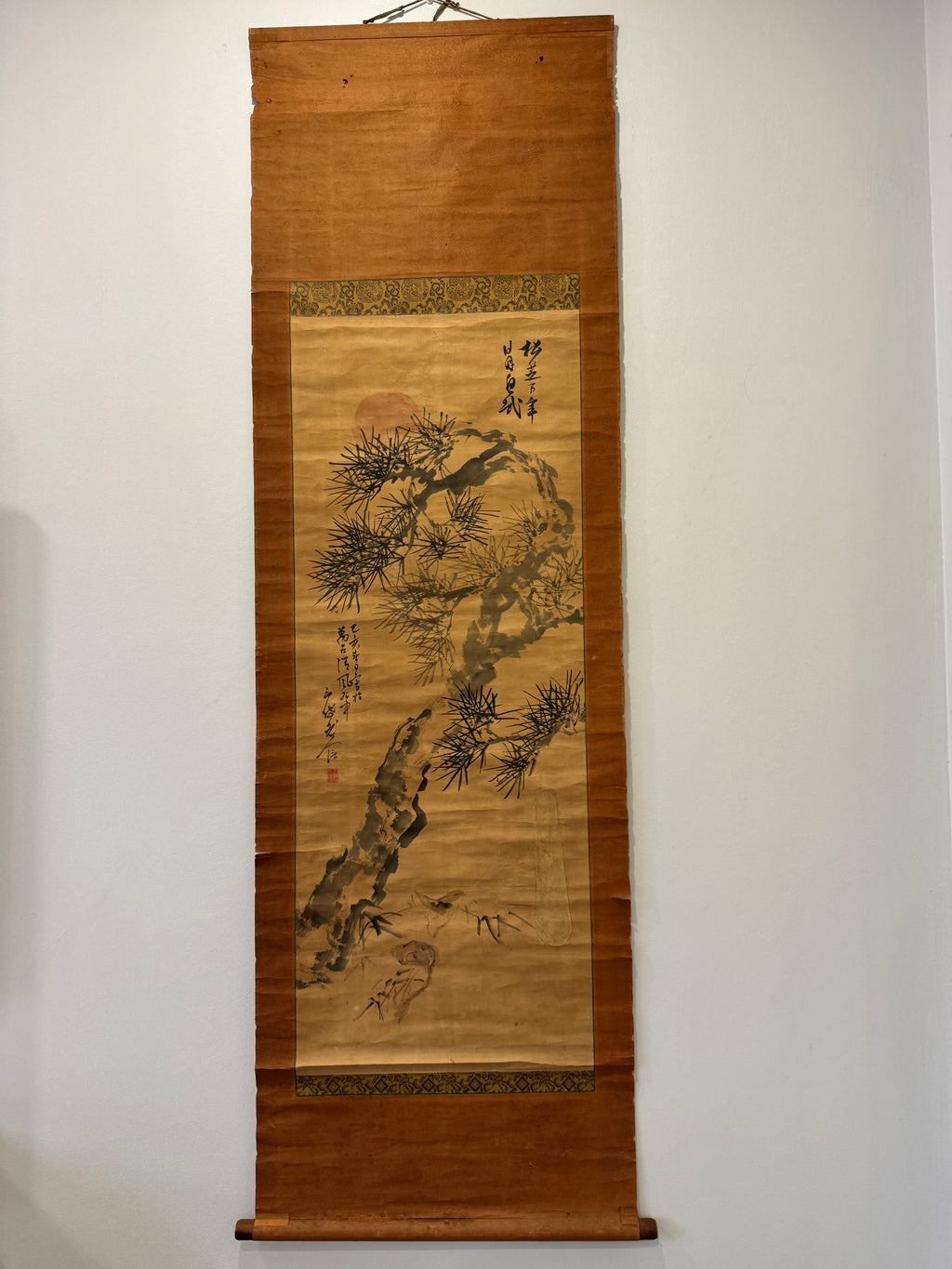 Traditional Japanese scroll with nature-themed artwork on a plain wall