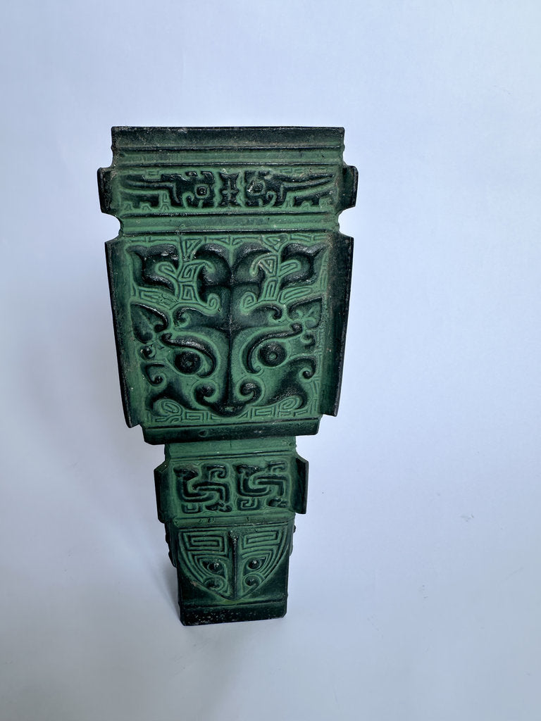 An ornate green decorative wall plaque with intricate carved Chinese-style patterns, photographed against a plain light background.