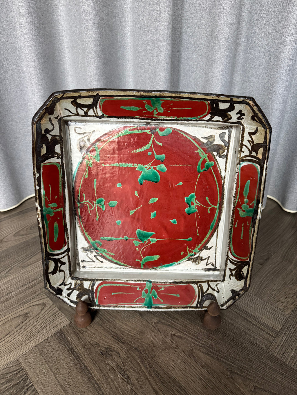 Decorative tray with red and green design on a wooden floor