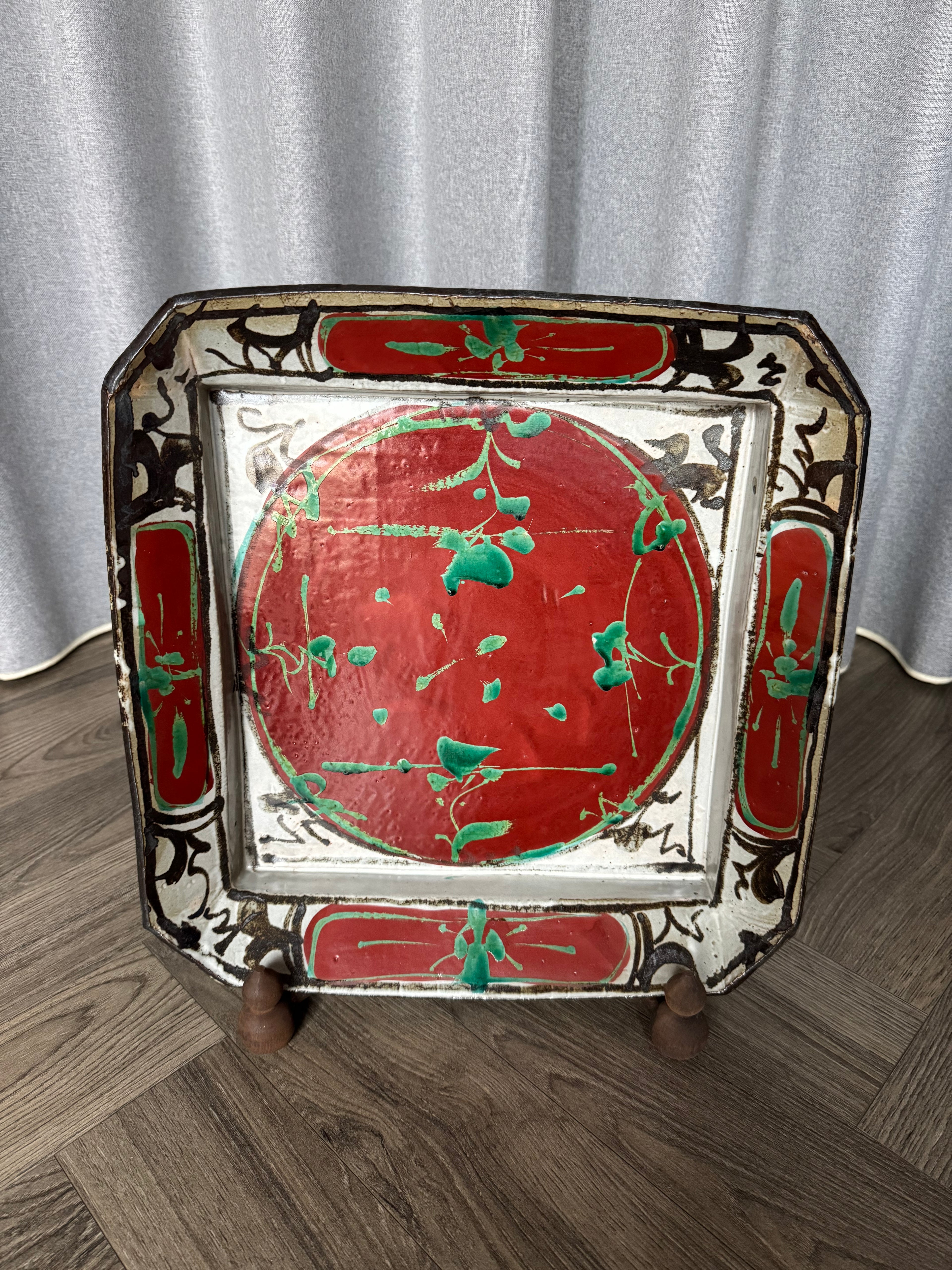 Decorative tray with red and green design on a wooden floor