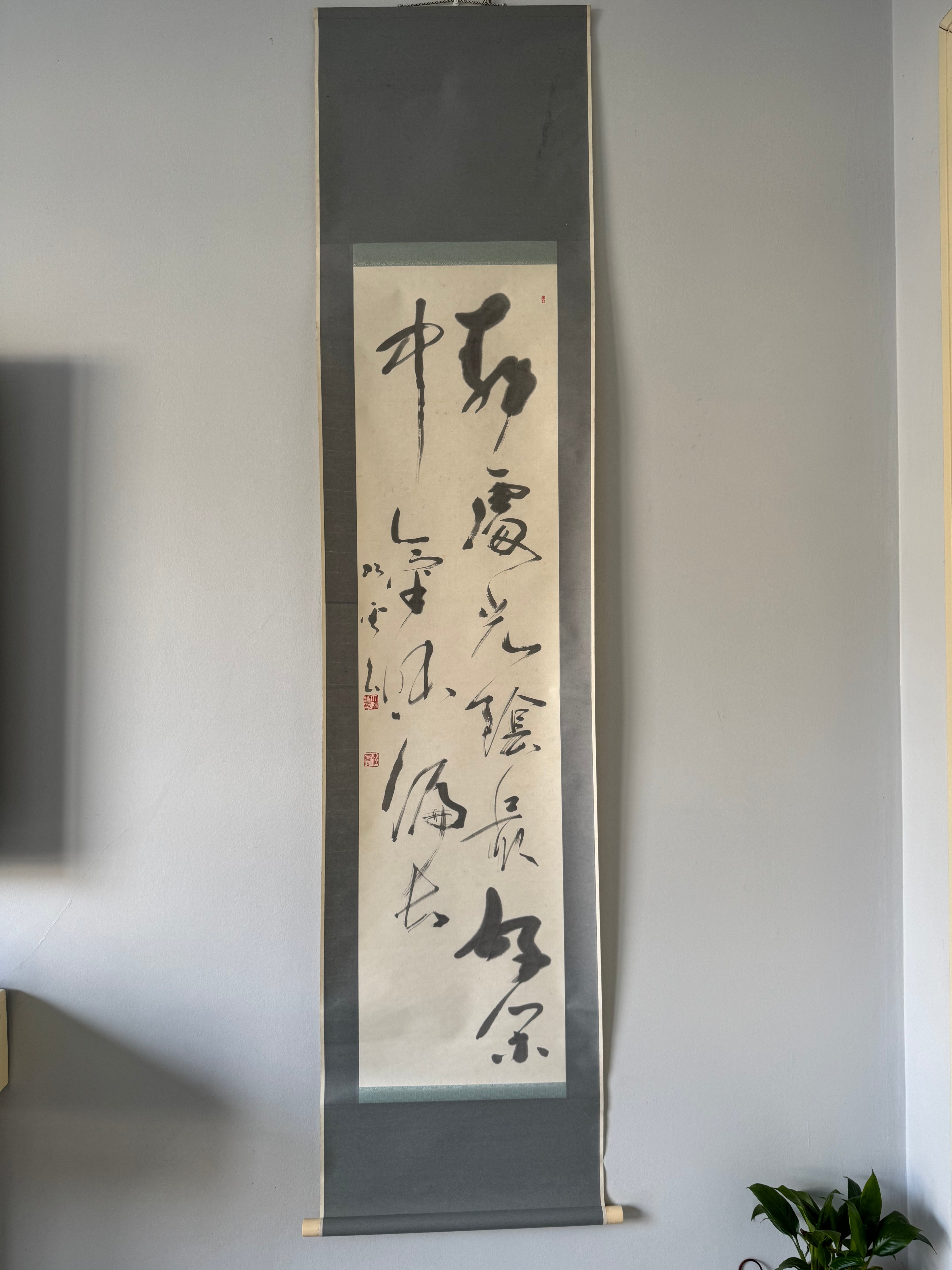 Vertical scroll with calligraphy on a plain wall