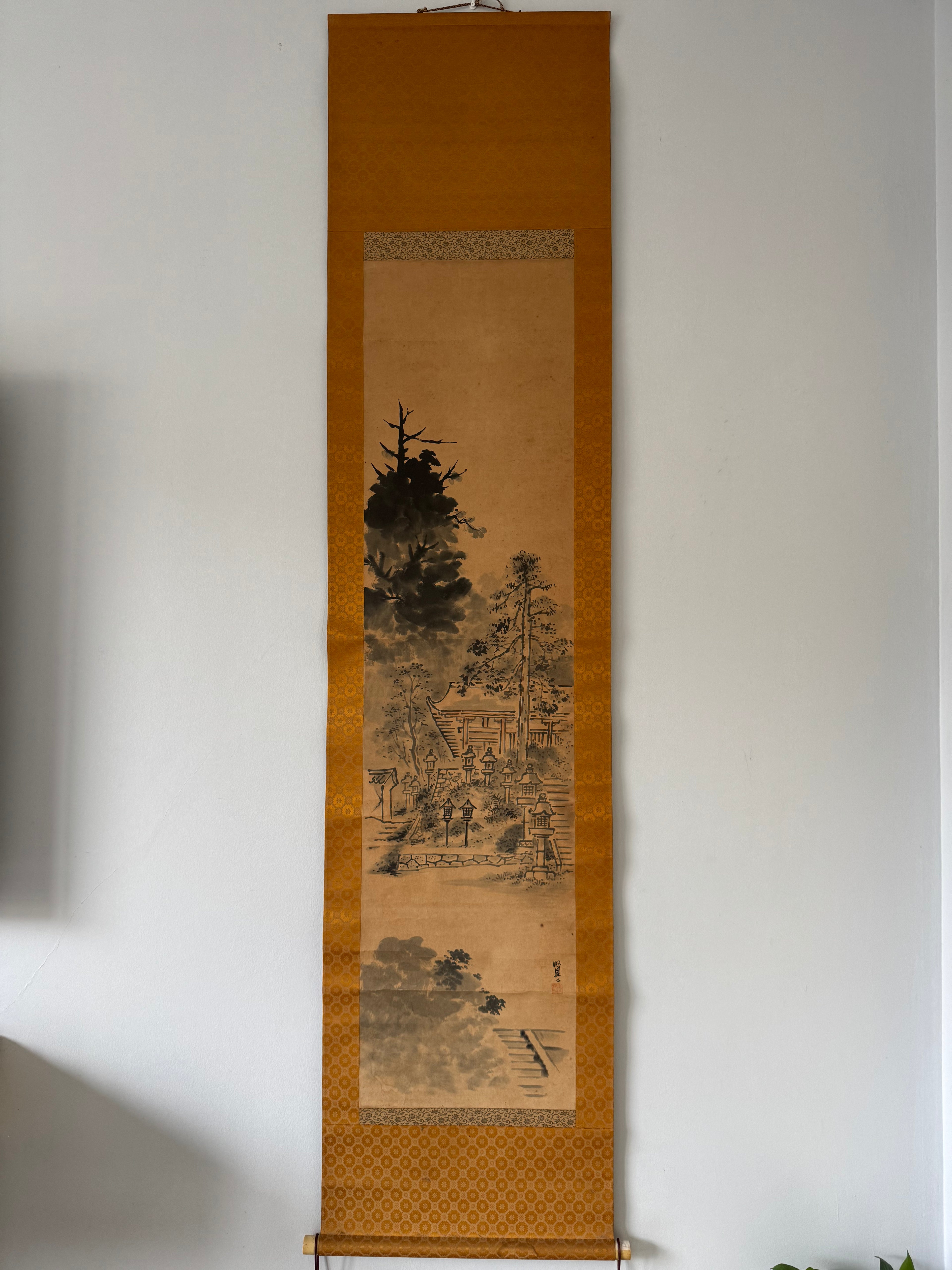 Traditional Japanese scroll painting on a stand against a plain wall