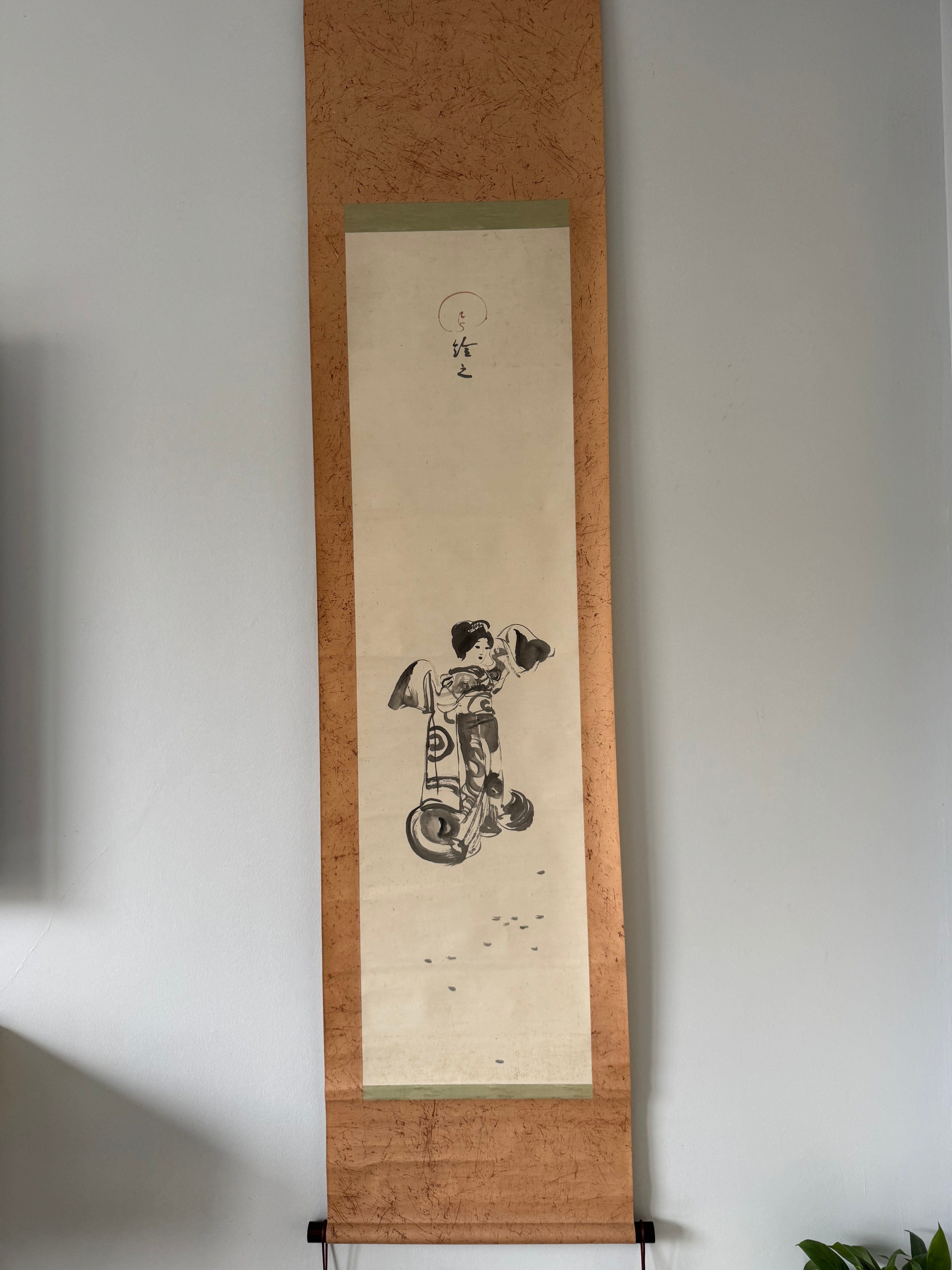Traditional Japanese scroll with artwork on a plain wall