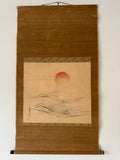 Traditional Japanese scroll with a red sun and landscape on a brown background