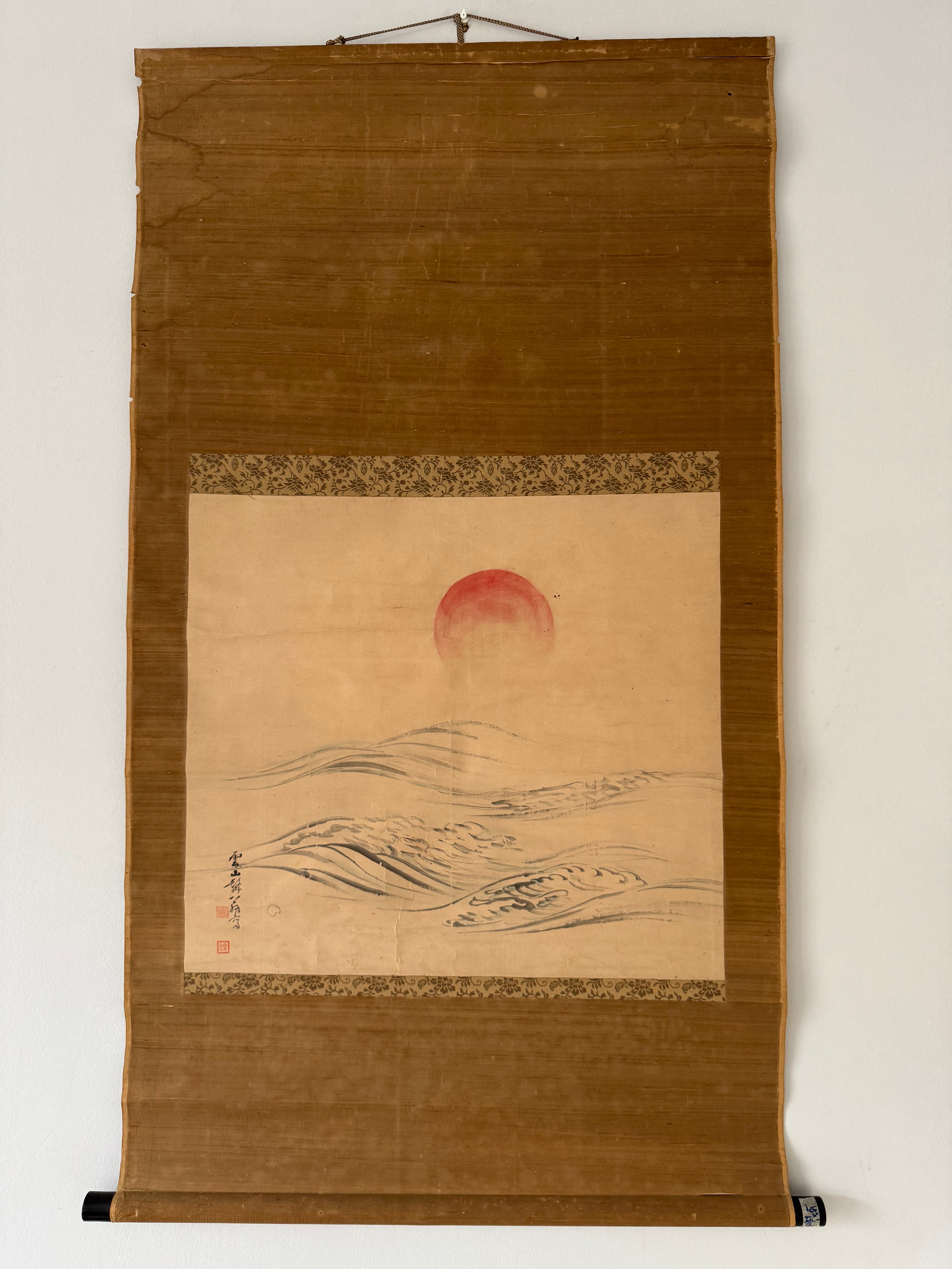 Traditional Japanese scroll with a red sun and landscape on a brown background