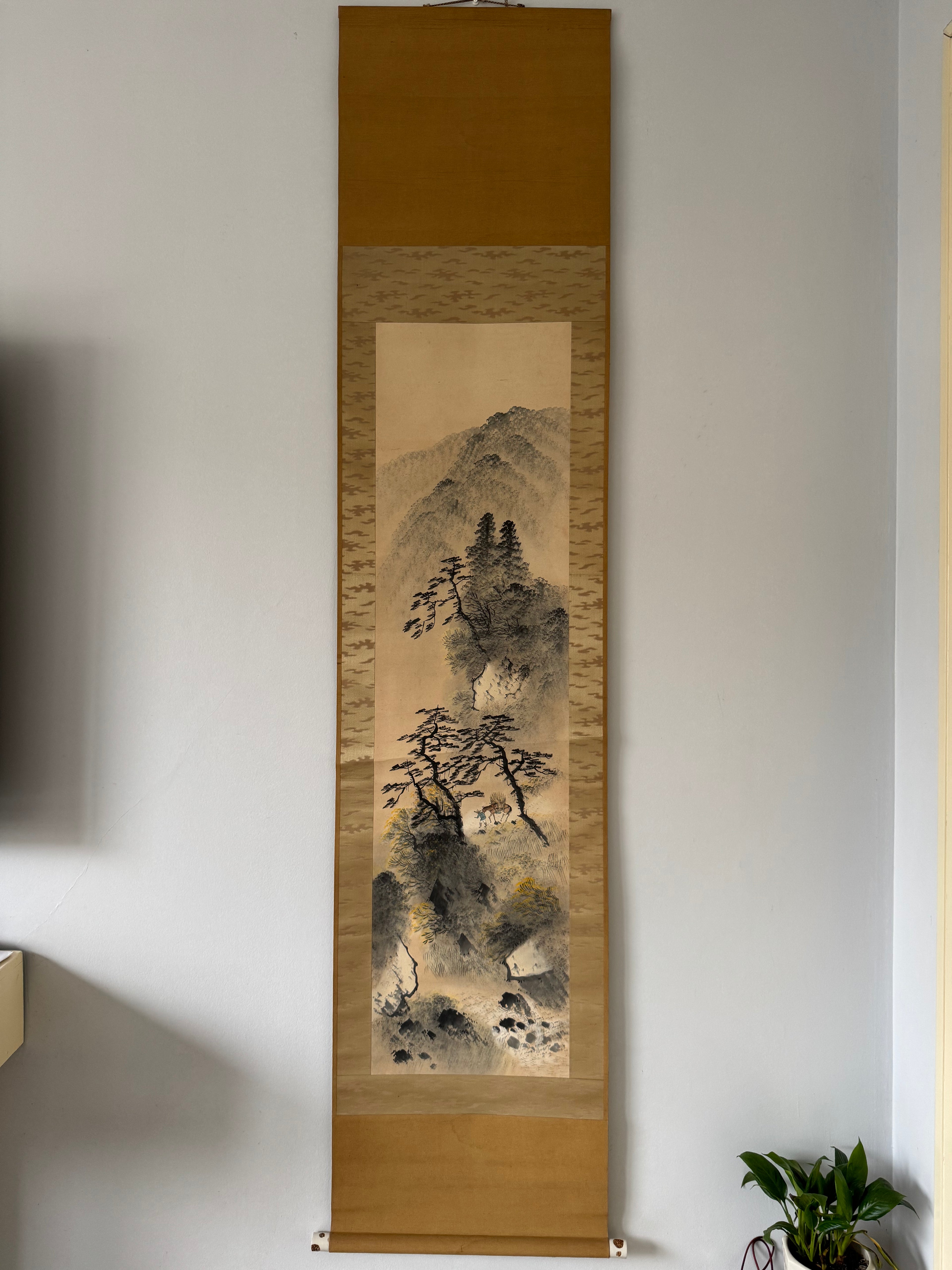 Vertical traditional Japanese painting on a wooden frame against a plain wall.