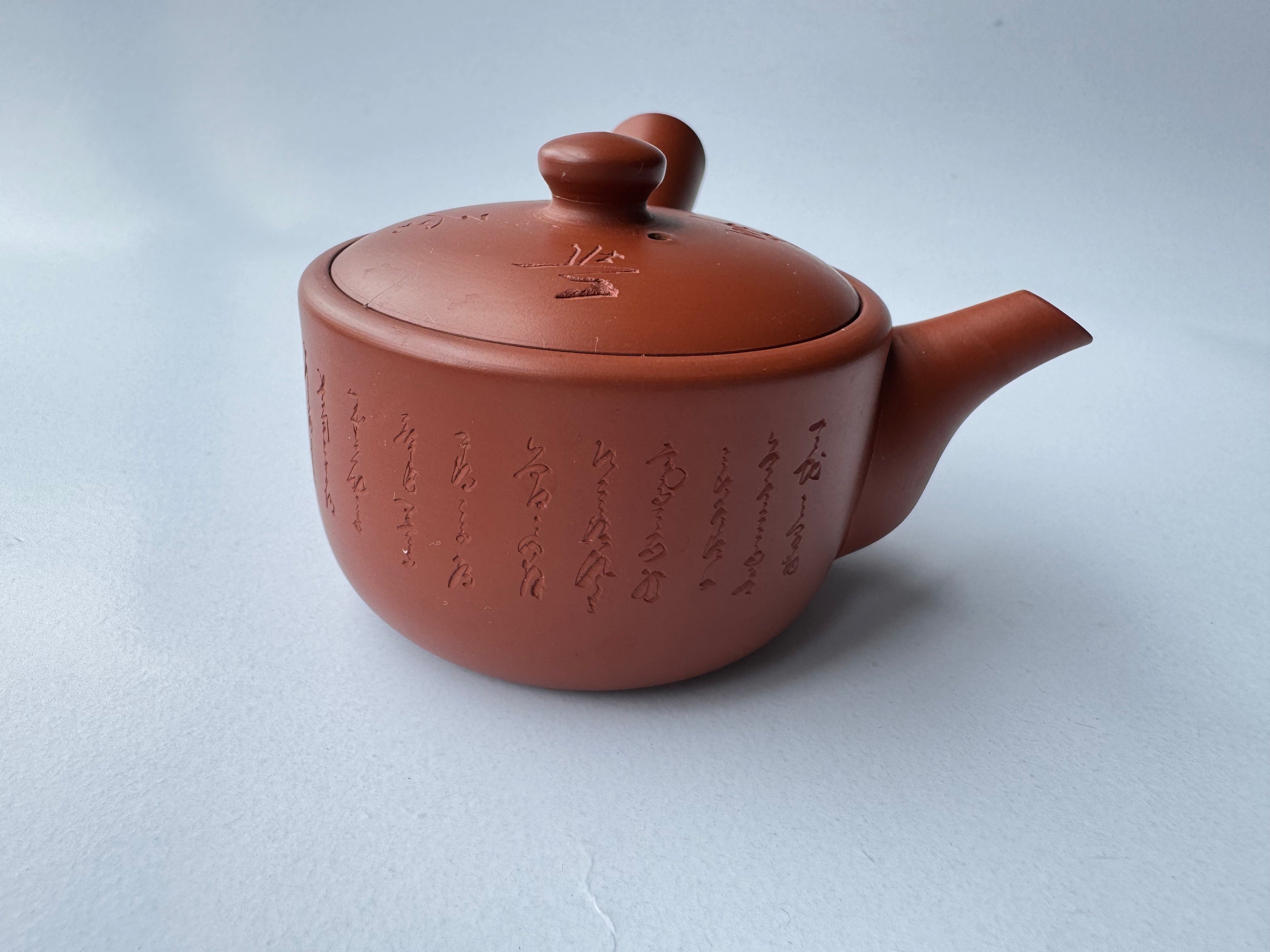 Red clay teapot with text on a light gray background