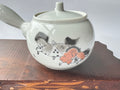 Ceramic teapot with floral design on a wooden surface