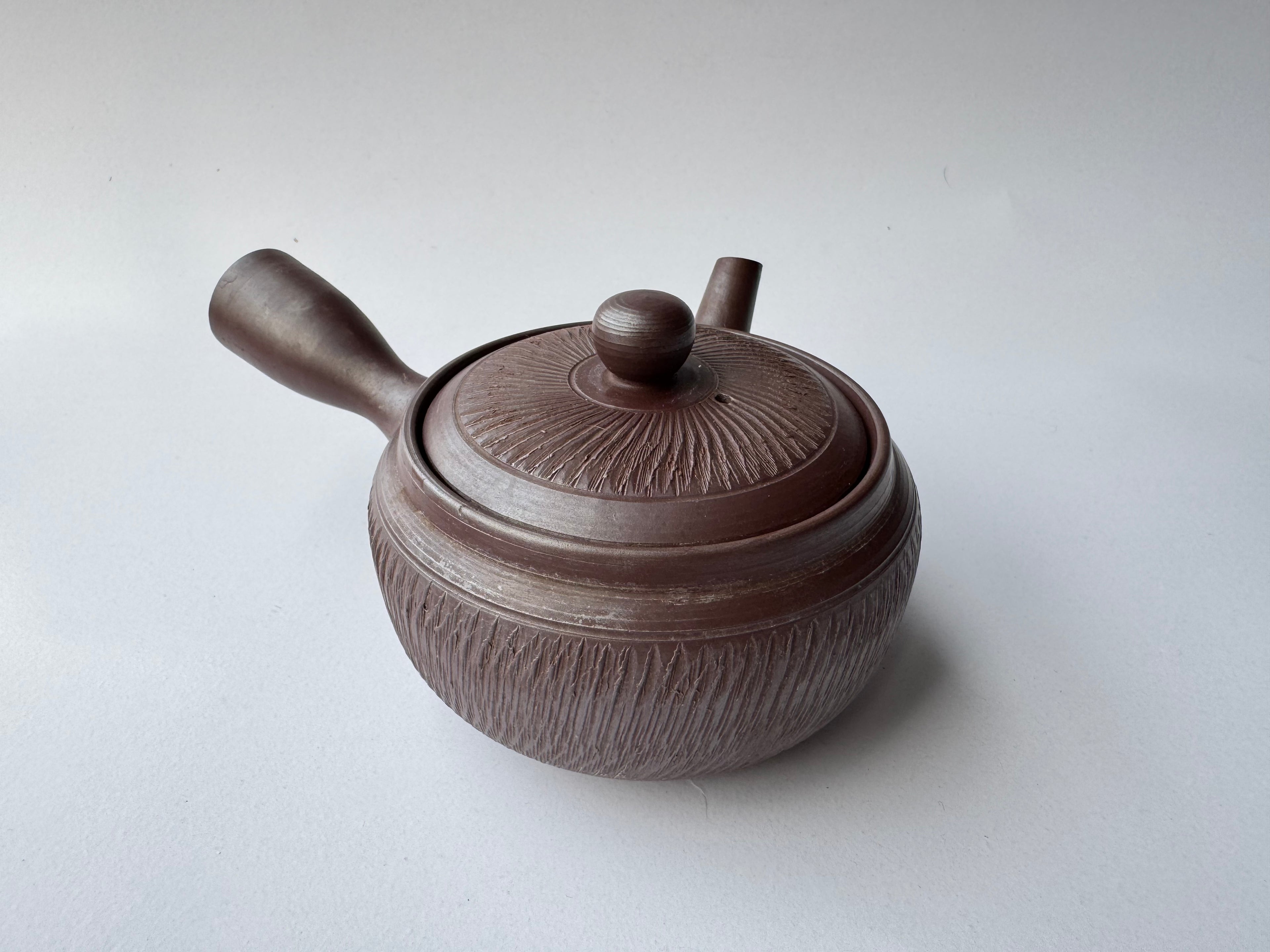 Brown ceramic teapot with lid on a white background