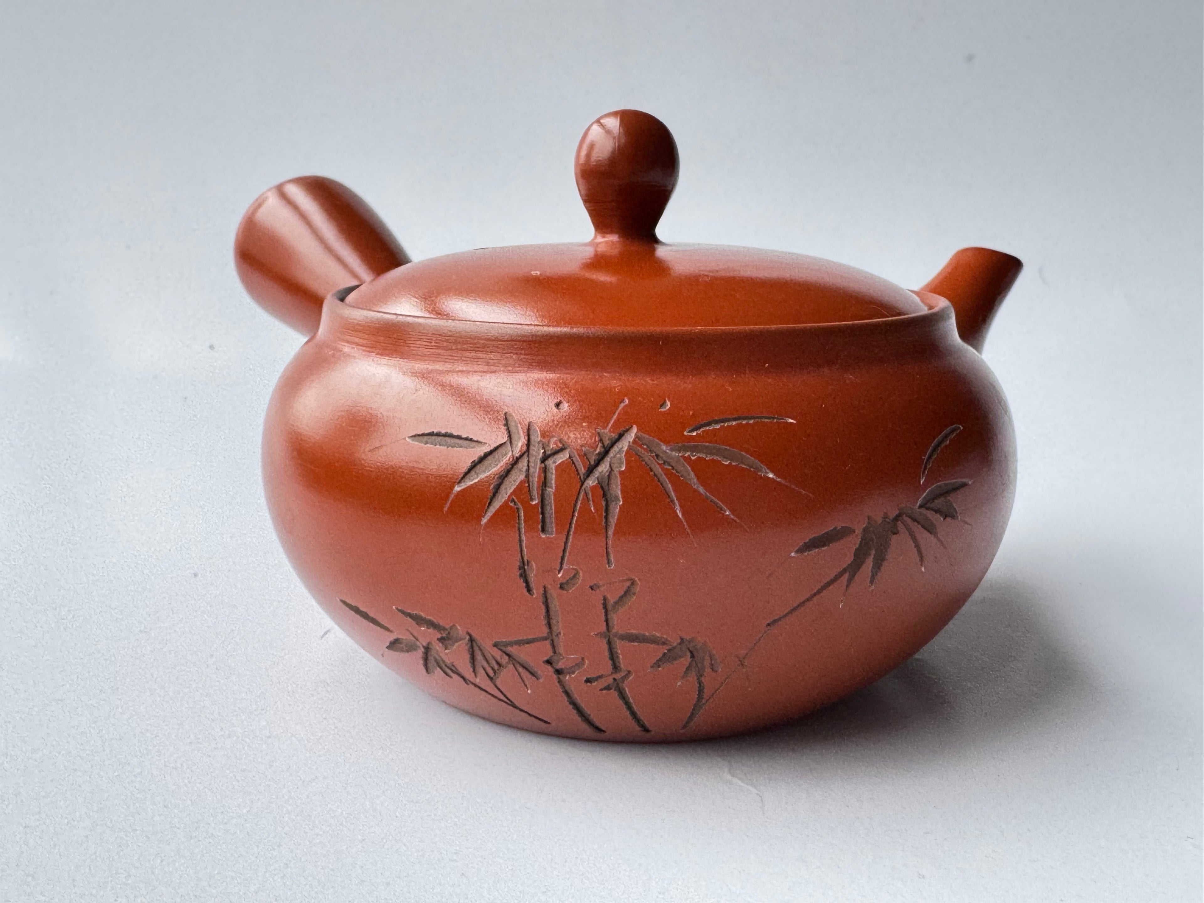 Red ceramic pot with bamboo design on a white background