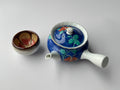 Ceramic teapot with floral design on a white background