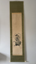 Traditional Japanese artwork on a vertical scroll hanging against a plain wall.