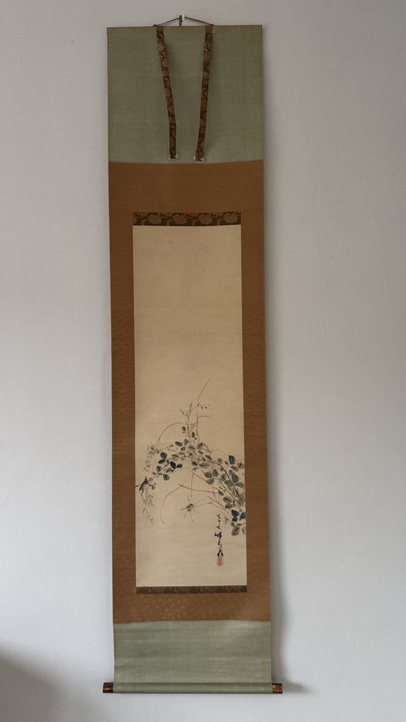 Traditional Japanese hanging scroll with floral design on a plain wall.