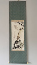 Traditional Japanes ink painting of a landscape with trees and rocks on a vertical scroll.