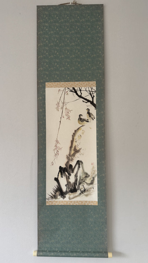 Traditional Japanes ink painting of a landscape with trees and rocks on a vertical scroll.