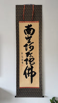 Traditional calligraphy scroll on a decorative frame against a white wall