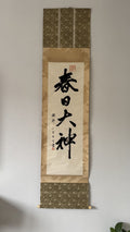 Calligraphy scroll with decorative border on a plain wall