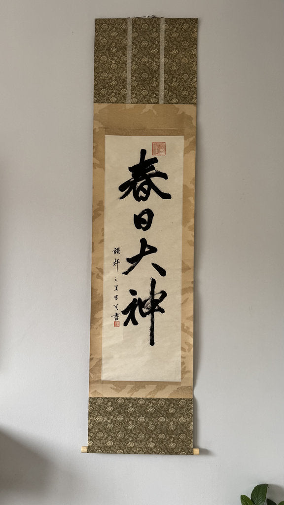 Calligraphy scroll with decorative border on a plain wall
