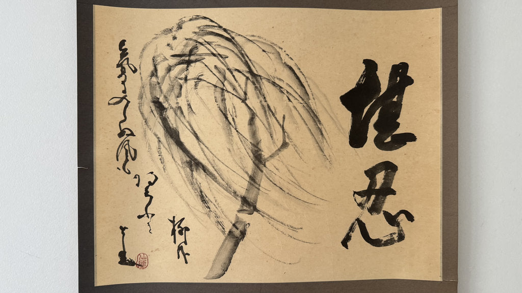 A framed calligraphic art print featuring a black ink painting of a willow branch on beige paper, with bold black Chinese characters on the right and calligraphic markings on the left, set against a light gray background.
