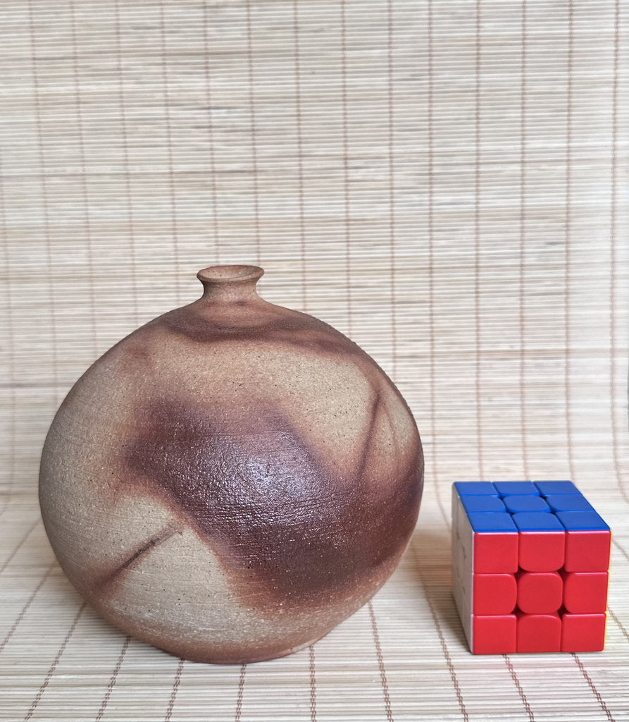 Ceramic vase and Rubik's cube on a woven mat
