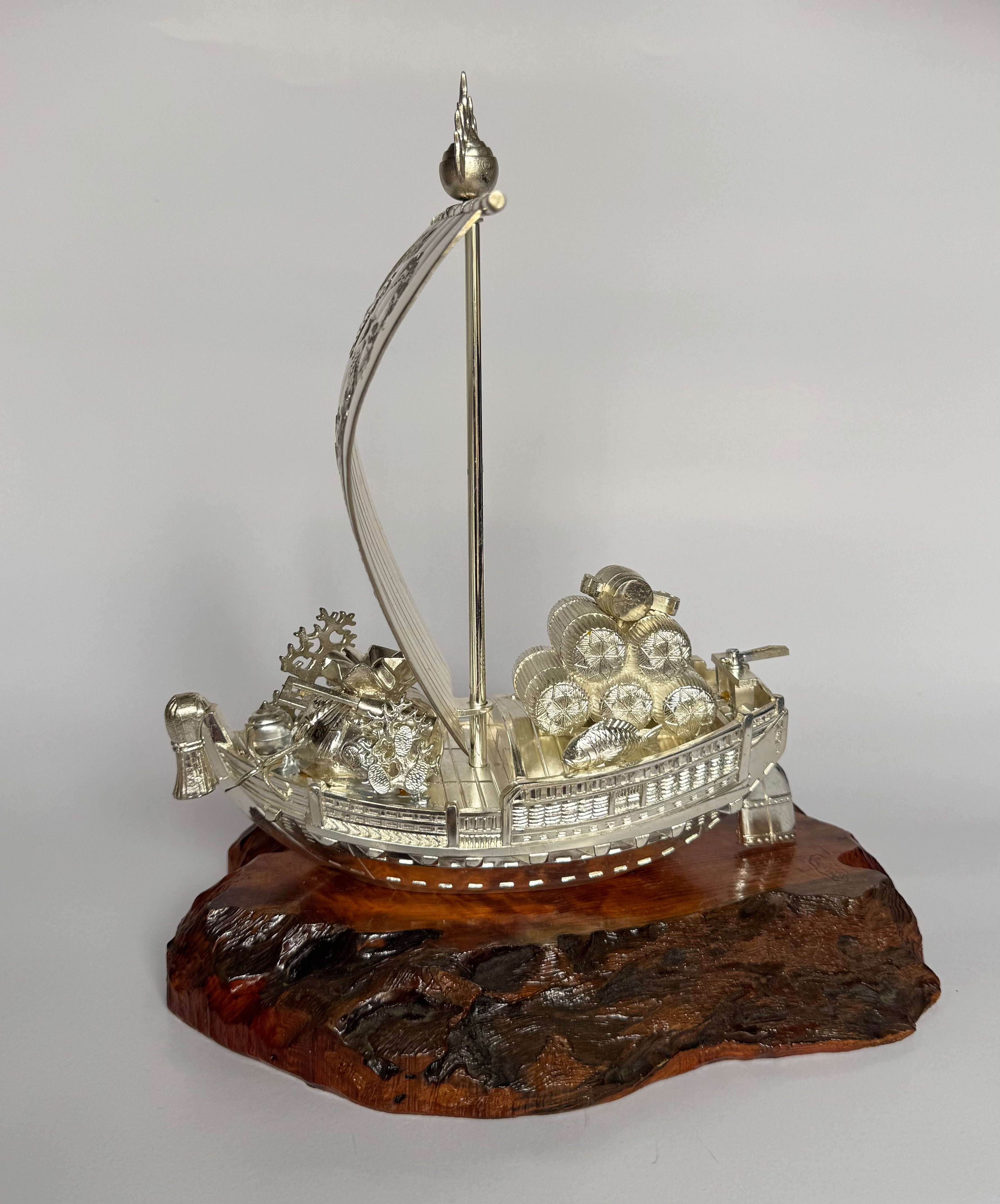 Decorative ship model on a wooden base against a plain background