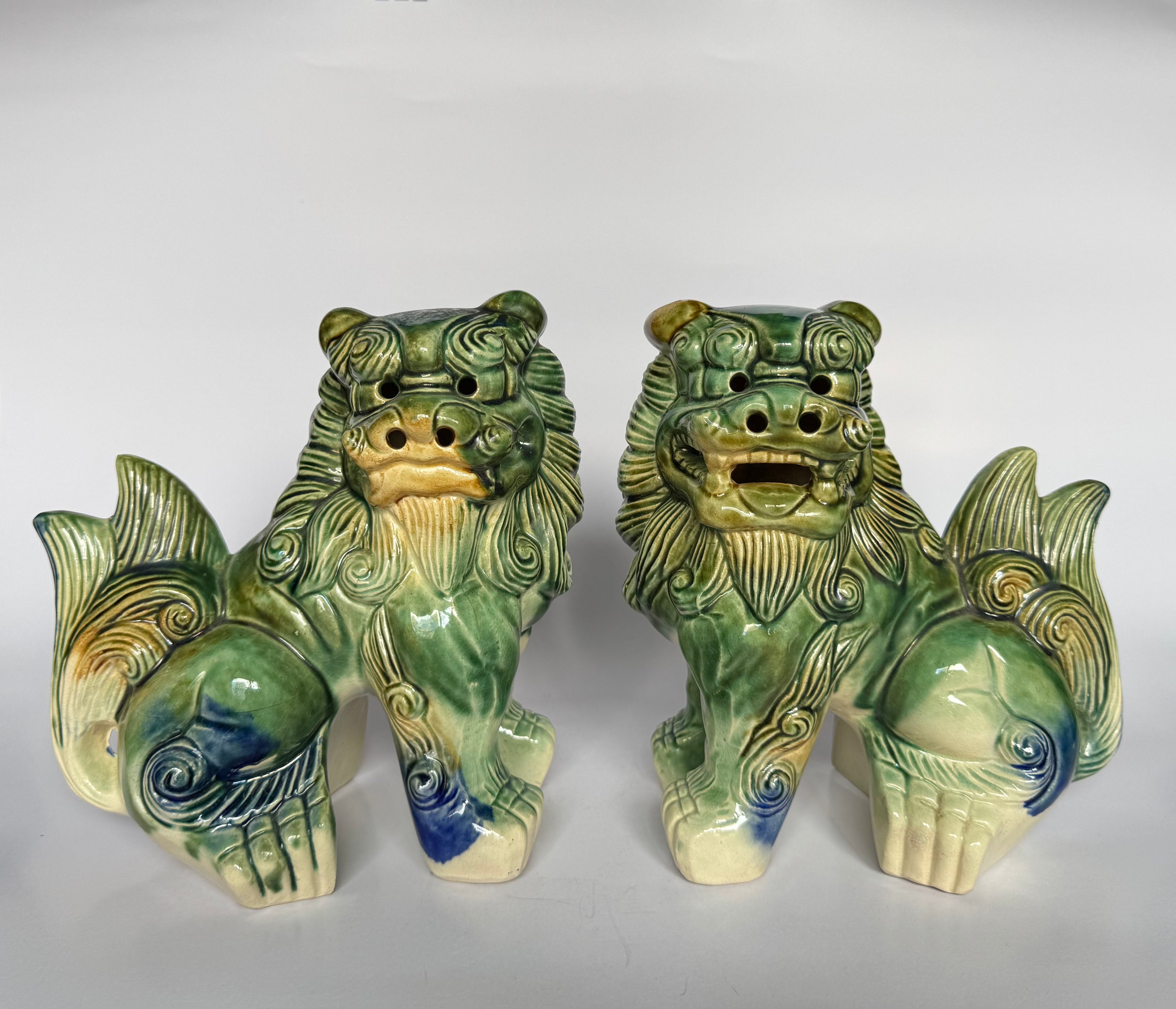 Two green ceramic lion statues on a white background