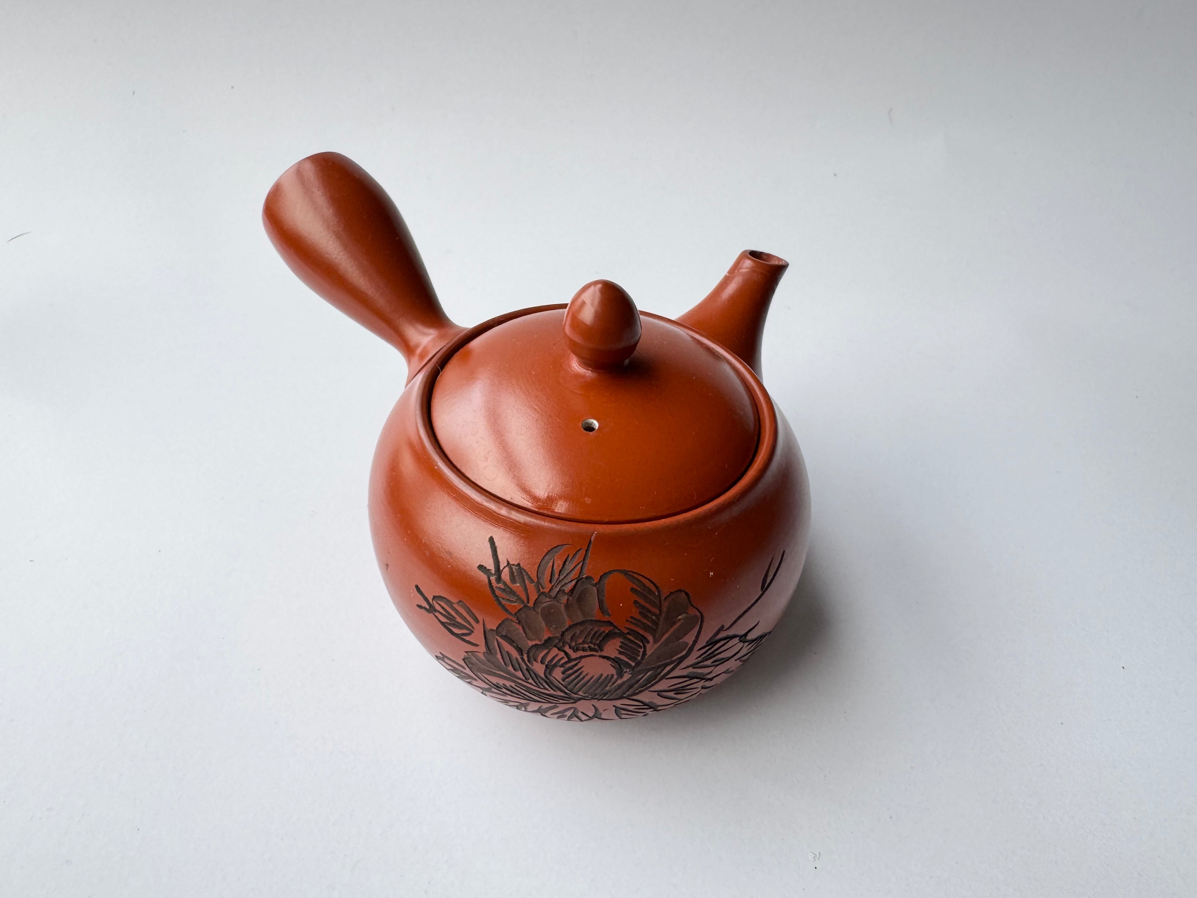 Ceramic teapot with floral design on a white background