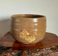 Brown ceramic bowl with a decorative design on a wooden surface