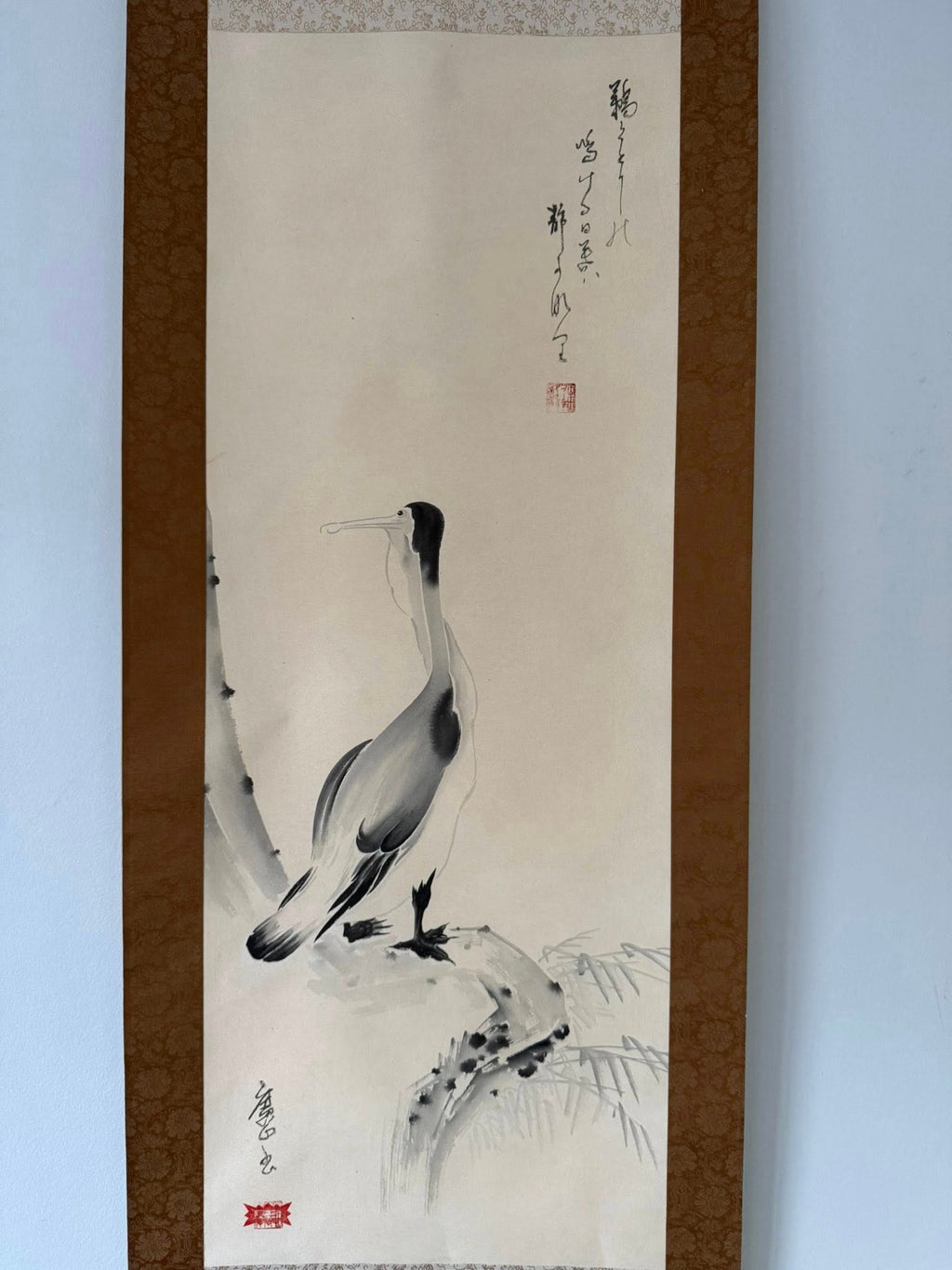 Traditional Japanese ink painting of a crane on a white background with brown frame.