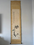 Traditional scroll with floral design and calligraphy on a plain wall.